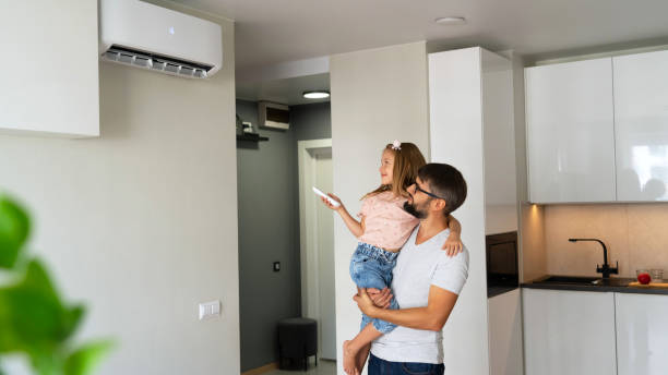 Père et fille réglant leur pompe à chaleur air/air dans la cuisine